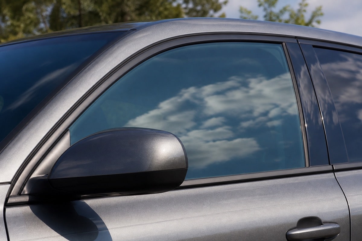 Tinted automotive glass reflecting a blue sky