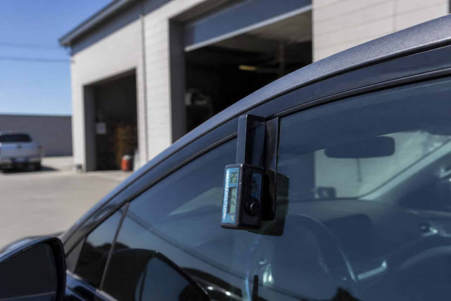 Handheld VLT meter measuring window tint percentage on a car window